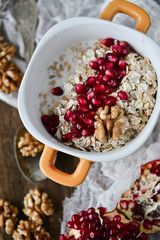 Breakfast: granola with pomegranate and walnuts on natural wooden background rustic. The concept of healthy and high-carbon nutrition.