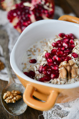 Breakfast: granola with pomegranate and walnuts on natural wooden background rustic. The concept of healthy and high-carbon nutrition.