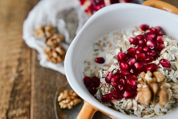 Breakfast: granola with pomegranate and walnuts on natural wooden background rustic. The concept of healthy and high-carbon nutrition.
