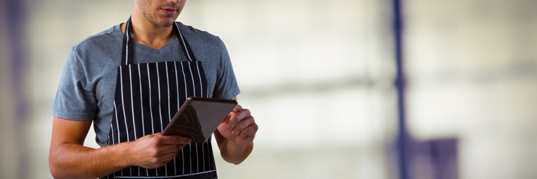Composite image of male waiter using digital tablet