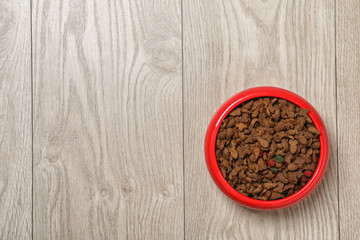 Bowl with food for cat or dog on wooden background. Pet care