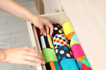 Fototapeta premium Woman opening drawer with different colorful socks indoors, closeup