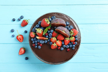 Fresh delicious homemade chocolate cake with berries on wooden table, flat lay
