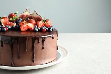 Fresh delicious homemade chocolate cake with berries on table against color background. Space for...