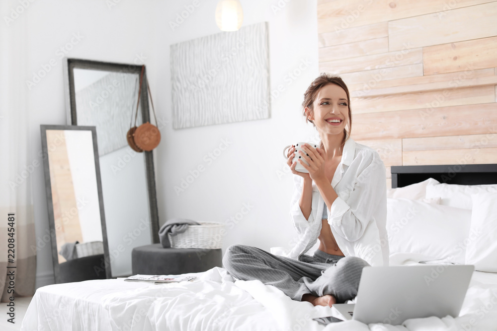 Canvas Prints Young happy woman with cup of aromatic coffee on bed at home. Lazy morning