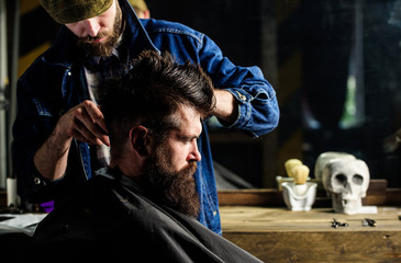 Hipster client getting haircut. Barber styling hair of brutal bearded client with clipper. Haircut...