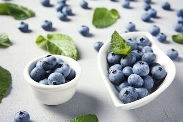 Juicy blueberries and green leaves on color table