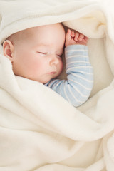 Baby sleeping covered with soft white blanket