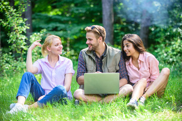 Fototapeta na wymiar Freelance opportunity. Modern technologies give opportunity to work in any environment conditions. Company youth spend leisure outdoors with laptop. Friends working with laptop at green meadow