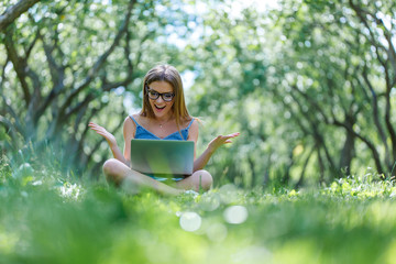 Young woman with notebook in park looking at notebook computer