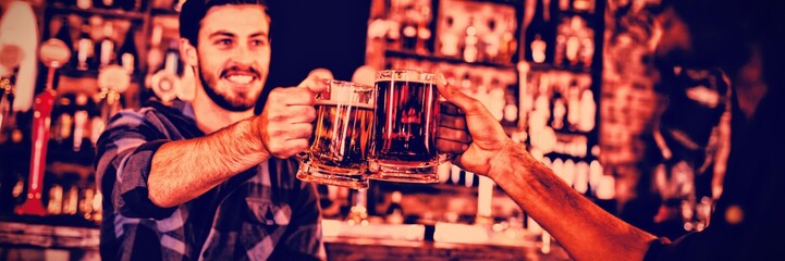 Two young men toasting their beer mugs