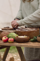 Medieval food preparation including bread, butter, cheese, fruit in wooden bowls or trenchers