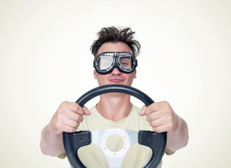 Man in stylish goggles with steering wheel on yellow background, car driver concept