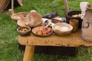 Typical selection of Medieval food including bread, butter, cheese, fruit and nuts served in wooden bowls or trenchers