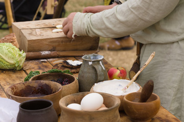 Medieval food preparation including bread, butter, cheese, fruit in wooden bowls or trenchers