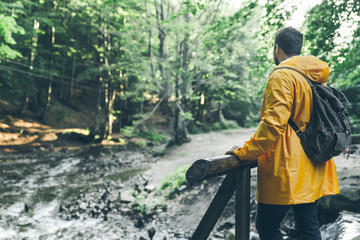 man stand in the middle of forest in yellow raincoat.