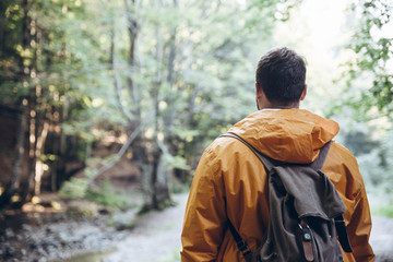 man stand in the middle of forest in yellow raincoat.