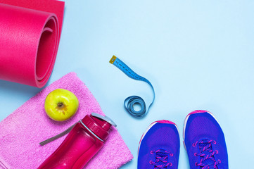 Fitness concept with Ultra violet pink female sneakers, water bottle, towel, apple on pastel blue background flat lay top view. Sports shoes, fitness, concept of healthy lifestile.