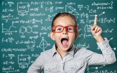 Genius boy in red glasses near blackboard with formulas