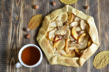 Homemade galette with different fruits with pears, peaches and nuts on wooden background