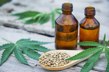 hemp leaves on wooden background, seeds, cannabis oil extracts jars