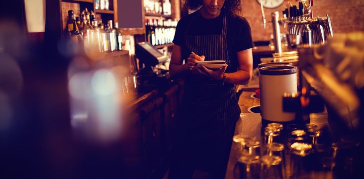 Young waiter writing on diary