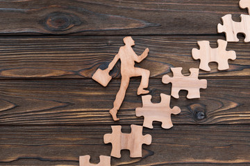 running up the worker on the steps of puzzles on a wooden background. career.