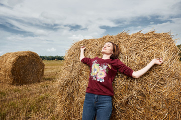 Naklejka na ściany i meble young girl having fun in the field, lying on a haystack