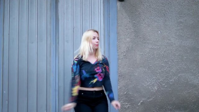 Blond hair girl funny dancing at the old wall of the city
