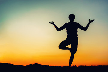 Silhouette of man in yoga pose at sunset