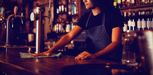 Young waiter cleaning a counter