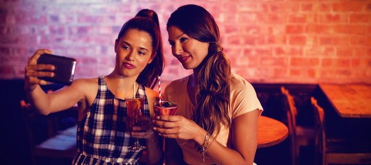 Young women taking a selfie while having cocktail drinks