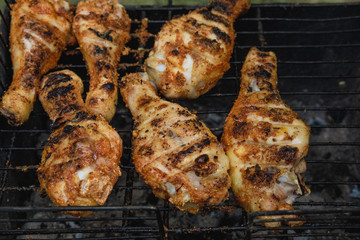 Fried chicken legs over the barbecue during cooking
