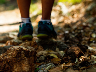 Feet of a man walking on fallen leaves in the woods