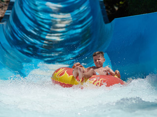 Boy having fun on the water slide in the aqua fun park.