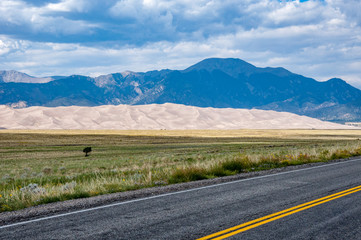 road, meadow, sand dunes, mountains and clouds