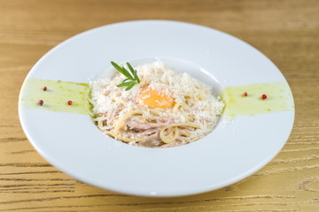 Spaghetti carbonara with bacon and egg on a white plate