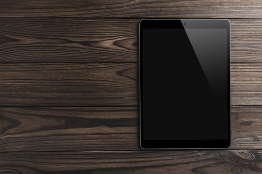Black tablet computer on wooden dark background with space for text, flat lay