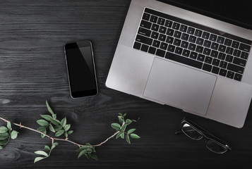 Modern workspace with notebook or laptop, smartphone and eyeglasses on wood texture background. Top view, flat lay style