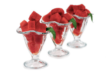 Pieces of chopped watermelon in beautiful glass vases, mint leaves, on a white background