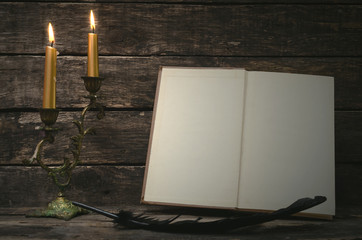 Open book with blank empty pages in the light of burning candle. Writer or author concept.