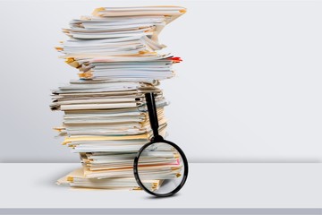 File folders with documents and magnifying glass on background
