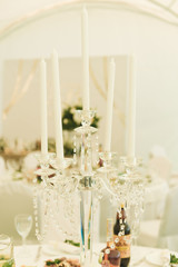Arch on festive table newlyweds covered with a tablecloth and decorated with composition of flowers and greenery, candles in the wedding banquet hall. Wedding party in tent.