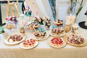 Naklejka premium Candy bar. Table with sweets at the wedding (cupcakes, cakes, marshmallows)
