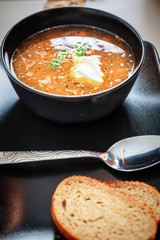 Pumpkin and carrot soup with cream and parsley in the black bowl