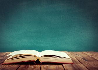 Open book on floor in front of blackboard