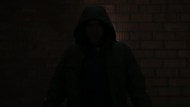 The maniac in a hood near a brick wall waits for the victim HD