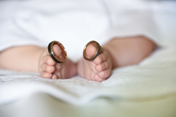 Baby wearing wedding rings on big toes