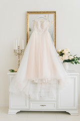 Fototapeta na wymiar wedding dress hanging on luster at hotel room