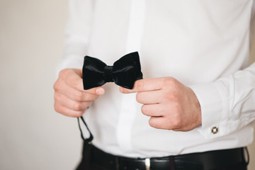 Grooms morning preparation, handsome groom with butterfly getting dressed and preparing for the...